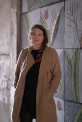 Kobieta w jasnym płaszczu na tle artystycznej ściany; dr Hanna Achremowicz, adiunktka w Instytucie Pedagogiki Uniwersytetu Wrocławskiego.