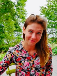 Kobieta w okularach na tle wnętrza, ubrana w jasny sweter.