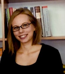 Dr Zuzanna Sury na tle regału z książkami, pracownik Instytutu Pedagogiki Uniwersytetu Jagiellońskiego.